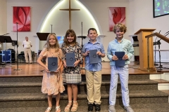 four young kids smiling at the camera holding Bibles