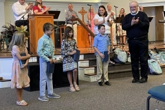 Church staff applaud four young kids holding Bibles